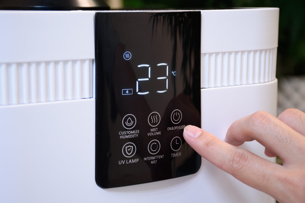 Close up of hand pressing button on thermostat or air conditioner